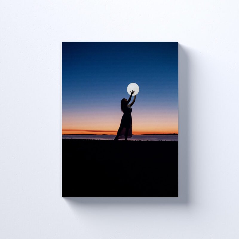 A Girl Holding Moon at Seaside Canvas Wall Art - Image 2